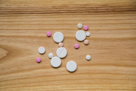 Lot of colorful pills on a wooden table. Different shapes and sizesの写真素材