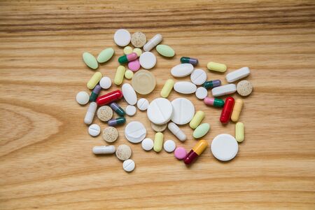 Lot of colorful pills on a wooden table. Different shapes and sizesの写真素材