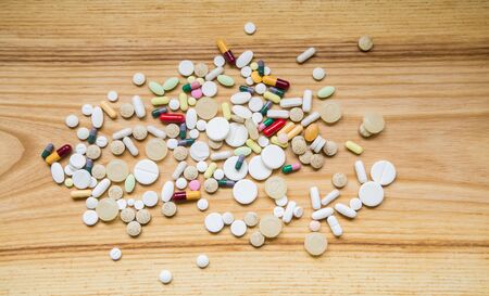 Lot of colorful pills on a wooden table. Different shapes and sizesの写真素材