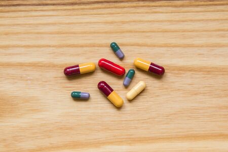 Lot of colorful pills on a wooden table. Different shapes and sizesの写真素材
