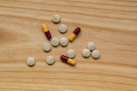 Lot of colorful pills on a wooden table. Different shapes and sizesの写真素材