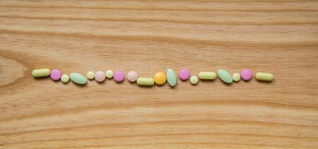 Lot of colorful pills on a wooden table. Different shapes and sizes