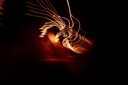 Red abstract trails of light on dark background. Long exposure.