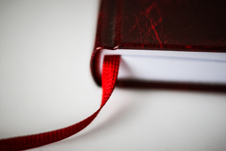 A beautiful closeup of a book in dark red cover and with red bookmark. Shallow depth of field