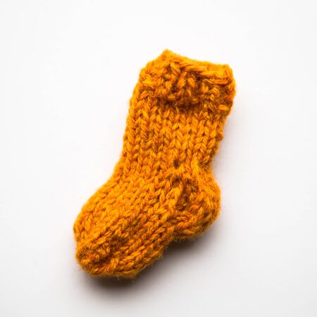 A small, hand knitted woolen sock on light backgroundの写真素材