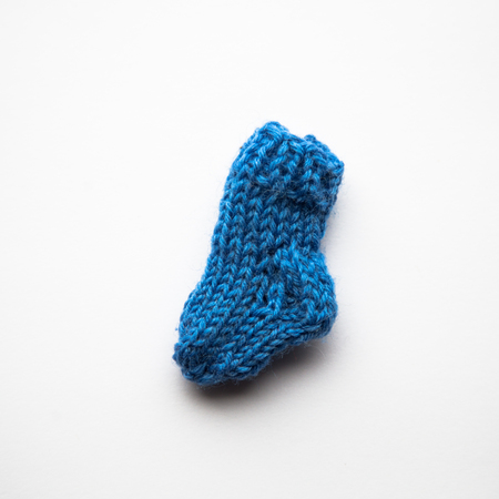 A small, hand knitted woolen sock on light backgroundの写真素材
