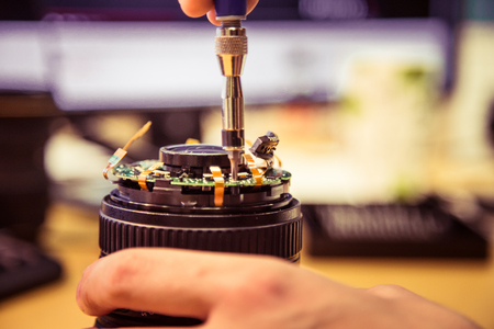 A man fixing photo camera lens on an office table