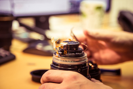 A man fixing photo camera lens on an office tableの写真素材