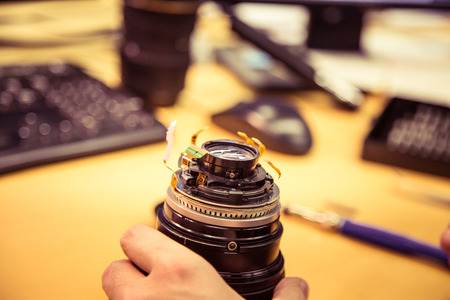 A man fixing photo camera lens on an office tableの写真素材
