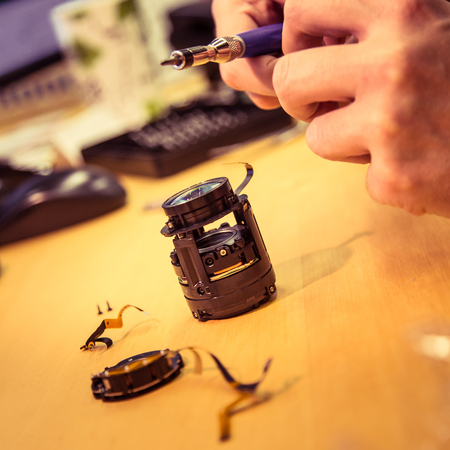 A man fixing photo camera lens on an office tableの写真素材