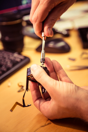 A man fixing photo camera lens on an office tableの写真素材