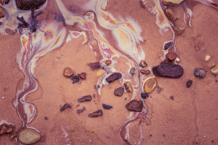 Colorful patterns of oil in the beach sand. Pollution patterns on the shore of Baltic sea. Colorful, abstract shapes on an ecological matter.の写真素材