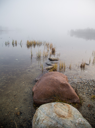 A beautiful morning scenery at the lake in Norway. Tranquil autumn landscape. Rock formation in a foreground. Colorful landscape with mist.の写真素材