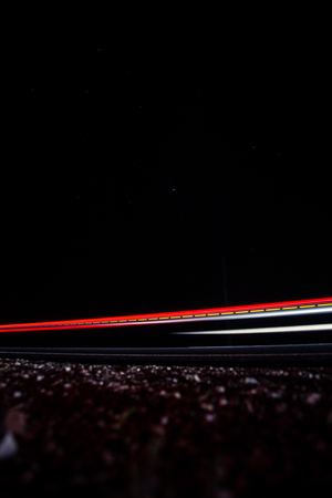 Beautiful, abstract car lights on a country road. TRaffic in the night, looking from a roadside. Long exposure photo.の写真素材