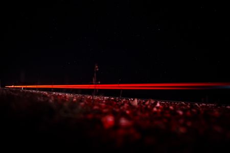 Beautiful, abstract car lights on a country road. TRaffic in the night, looking from a roadside. Long exposure photo.の写真素材