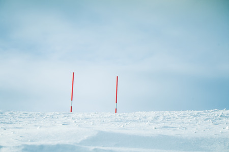 A beautiful white snowy road in central Norway with a red safety poles. Minimalist winter scenery un...