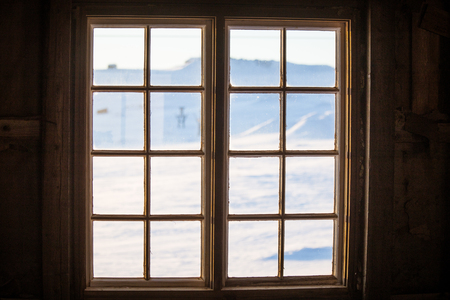 Beautiful wooden window with frozen ice flowers in Norwegian town.の写真素材