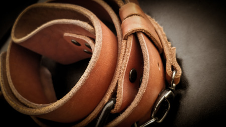 A beautiful brown hand made leather camera sling strap on a black background. Photographer...