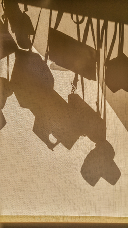 An abstract photo camera cases silhouettes on a fabric blind. SUn shining through window, making...