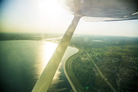 A beautiful aero landscape looking out of a small plane window under the wing. Riga, Latvia, Europe in summer. Authentic flying experience in a sunny, hazy day. Landscape from air.の写真素材
