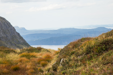 A beautiful autumn landscape of mountains in Folgefonna National park with fjord far in the distance. Fall scenery of southern Norway, Autumn colors in overcast day.の写真素材