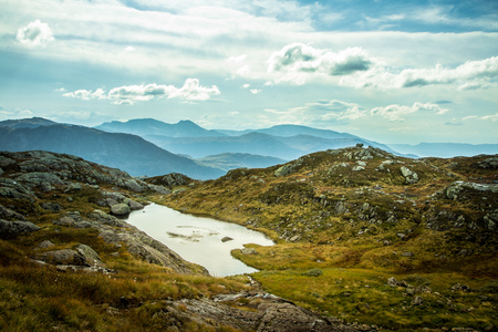 A beautiful autumn mountain landscape with a small lake. Natural scenery in Norwegian mountains. Small water pond in mountains.の写真素材