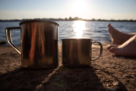 A beautiful riverside scenery with a metal cup of drinks.  Summertime sunset at the river.の写真素材