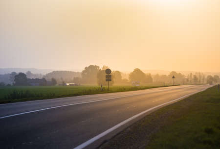 A beautiful summer morning scenery of countryside with an asphalt road. Summertime scenery of...