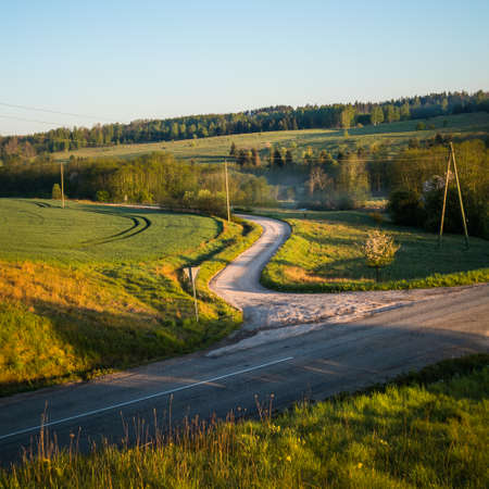 A beautiful summer morning scenery of countryside with an asphalt road. Summertime scenery of...
