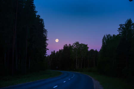 A beautiful full moon shining low in the sky during the summer dawn. Summertime scenery of Northern Europe.の写真素材