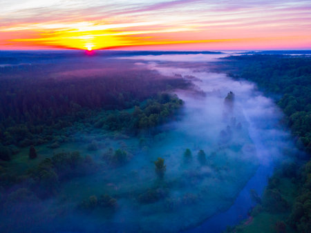 Drone's Eye View: Serene Sunrise Over Misty River and Woodland Landscape in Northern Europeの写真素材