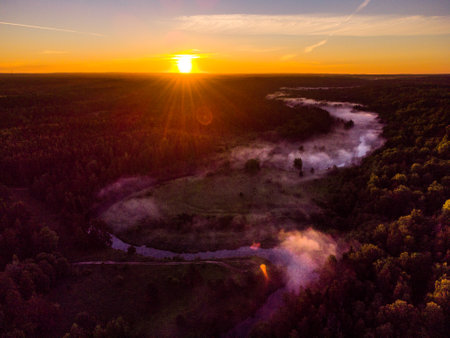 Drone's Eye View: Serene Sunrise Over Misty River and Woodland Landscape in Northern Europeの写真素材