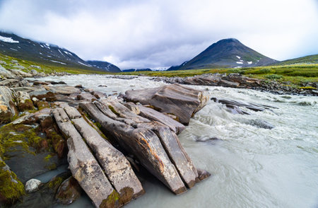 A wild, turbulent mountain river in the Sarek National Park, Sweden. A summer scenery with water in...