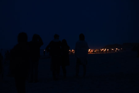A beautiful, dark scenery of people walking with fire torches on the beach of Baltic Sea during the fire festival. Summer festivities in the night.の写真素材