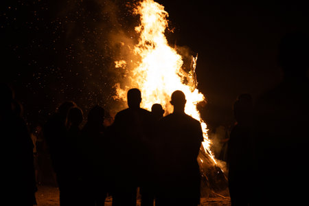 People watching the fire burn on the beach of Baltic sea during Fire Festival in summer. Bright, hot fire.の写真素材