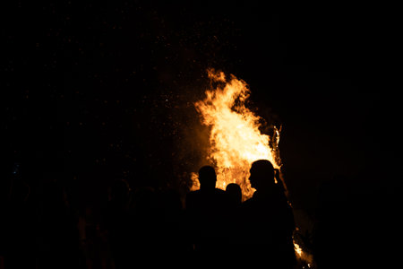 People watching the fire burn on the beach of Baltic sea during Fire Festival in summer. Bright, hot fire.の写真素材