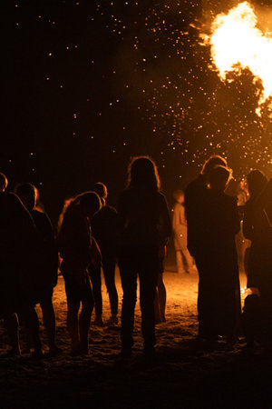 People watching the fire burn on the beach of Baltic sea during Fire Festival in summer. Bright, hot fire.の写真素材