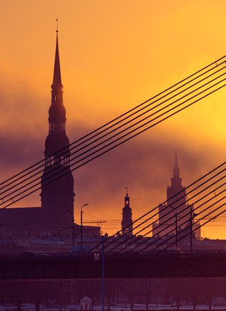 A beautiful Riga cityscape with suspension bridge over the riwer during colorful sunrise. Buildings against colorful sky. Norther Europe morning with warm sky.の写真素材