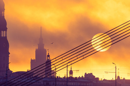 A beautiful Riga cityscape with suspension bridge over the riwer during colorful sunrise. Buildings against colorful sky. Norther Europe morning with warm sky.の写真素材