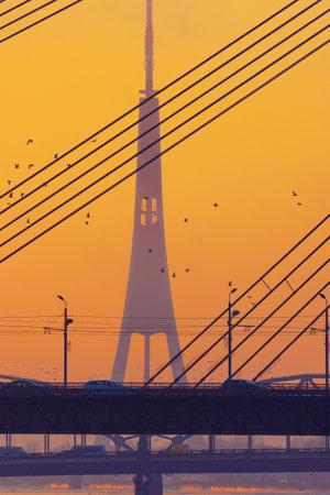 A beautiful Riga cityscape with suspension bridge over the riwer during colorful sunrise. Buildings against colorful sky. Norther Europe morning with warm sky.の写真素材