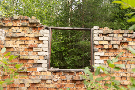 A broken, empty window of building ruins from Soviet times. Collapsed brick wall with window. Latvia, Europe.の写真素材