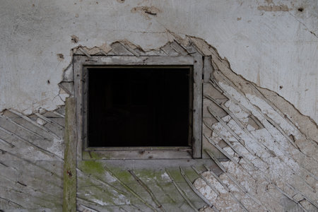 An old, broken window of a rural homestead in Latvia, Europe. Overgrown ruin of collapsed, abandoned house.の写真素材