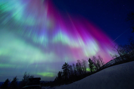 A beautiful aurora borealis display over the snowy Norwegian winter landscape. Northern lights in Norway sky. Arctic nature in Scandinavia during winter season.の写真素材