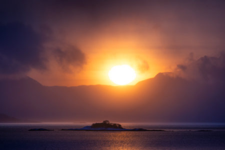A beautiful sun shining over the snowy mountains and fjord during the first day of arctic winter. Arctic nature in Scandinavia during winter season.の写真素材