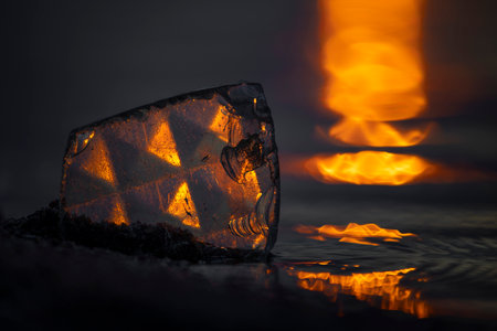A beautiful faceted glass shard reflecting sunset sun at the Baltic Sea beach. Artistic evening scenery in Latvia, Europe.の写真素材