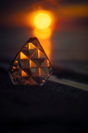 A beautiful faceted glass shard reflecting sunset sun at the Baltic Sea beach. Artistic evening scenery in Latvia, Europe.の写真素材
