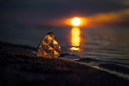 A beautiful faceted glass shard reflecting sunset sun at the Baltic Sea beach. Artistic evening...
