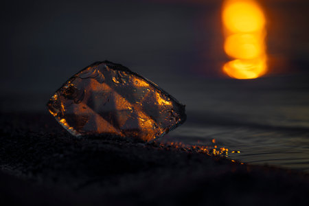 A beautiful faceted glass shard reflecting sunset sun at the Baltic Sea beach. Artistic evening...