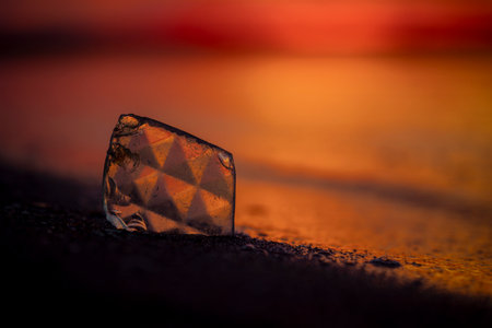 A beautiful faceted glass shard reflecting sunset sun at the Baltic Sea beach. Artistic evening scenery in Latvia, Europe.の写真素材