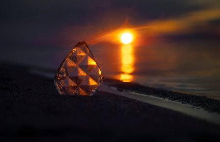 A beautiful faceted glass shard reflecting sunset sun at the Baltic Sea beach. Artistic evening...